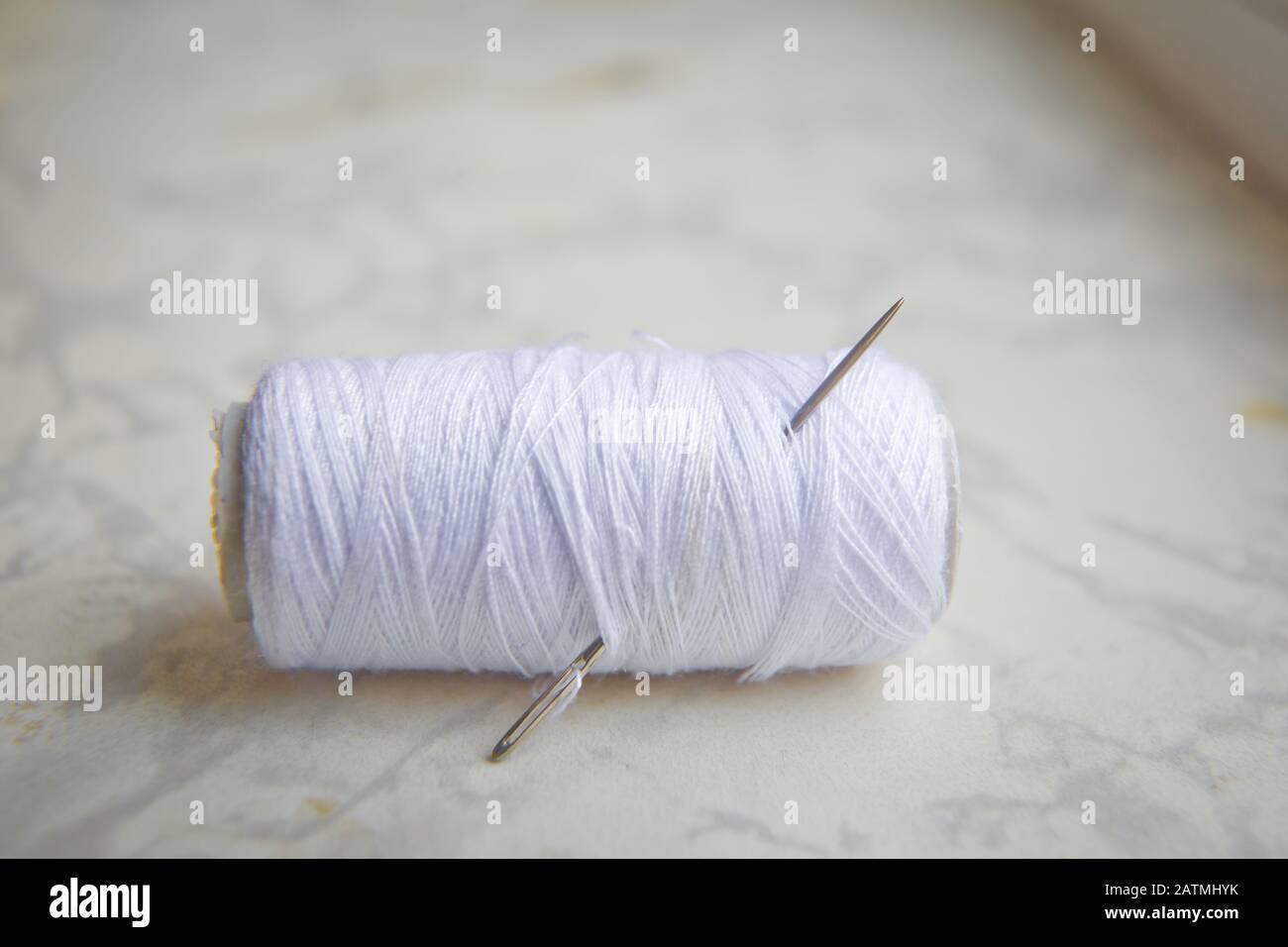 Bobine blanche avec aiguille isolée sur blanc .gros-plan de fil à coudre avec aiguille à broder. Métiers d'art et concepts de bricolage . Aiguille sur filetage blanc blanc Banque D'Images