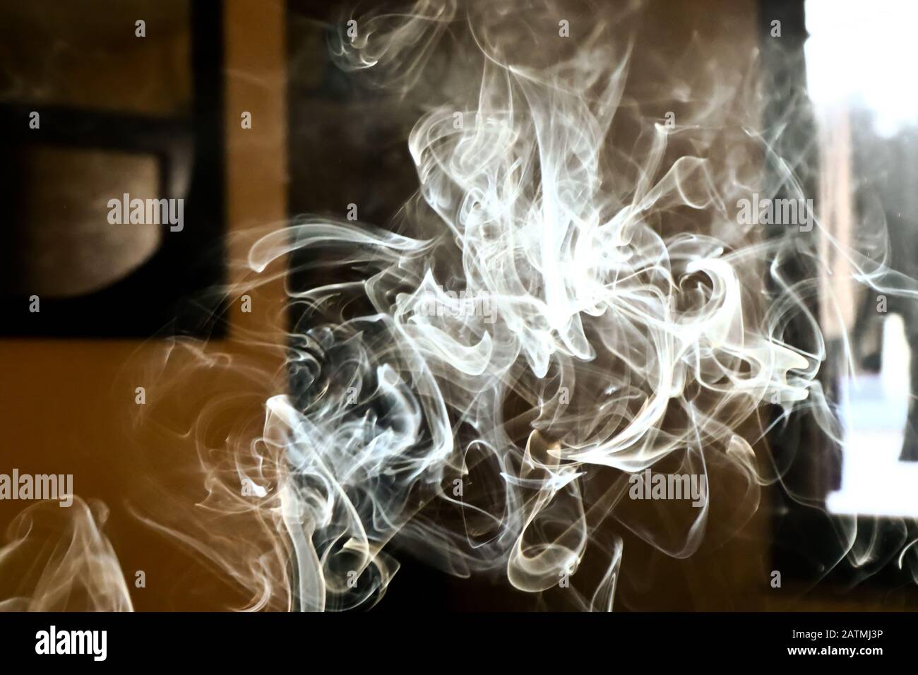 La vapeur de fumée dans la chambre s'éclaircit par la lumière du soleil, des boucles de vapeur brumeuses pour un effet spécial décoratif, un fond abstrait de fumée de cigarette Banque D'Images