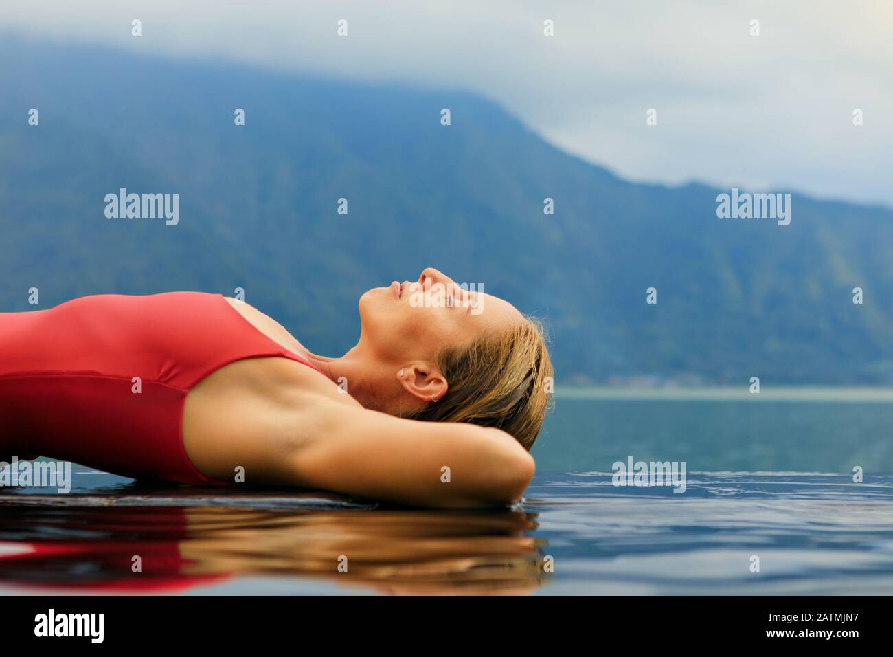 Jeune femme se détendre dans la piscine à débordement avec vue sur le lac. Spa naturel chaud sous le volcan Batur. Voyage À Kintamani, Bali. Un style de vie sain, Banque D'Images