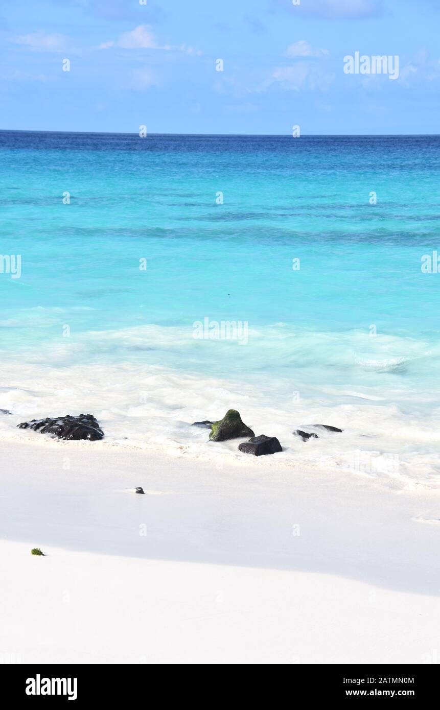 Plage tropicale de sable et eau bleu turquoise sous le ciel bleu et les pierres de lave Banque D'Images