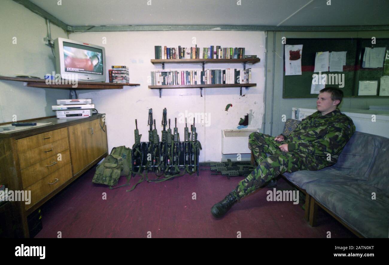 L'armée britannique a habité l'une des dernières tours de montres, le Golf Zero One, en regardant la zone du conseil d'administration du sud d'Armagh, en Irlande du Nord. Les membres du Parachute Regiment sont assis à l'intérieur de leur conteneur en acier qui agit comme leur compartiment de vie et regardent les bandes vidéo et la télévision tandis que leurs armes sont empilées dans le coin. Cette mini base a été retirée quelques jours plus tard par l'équipe d'ingénieurs de l'Armée de terre dans le cadre du retrait de l'Armée britannique de la région. Banque D'Images