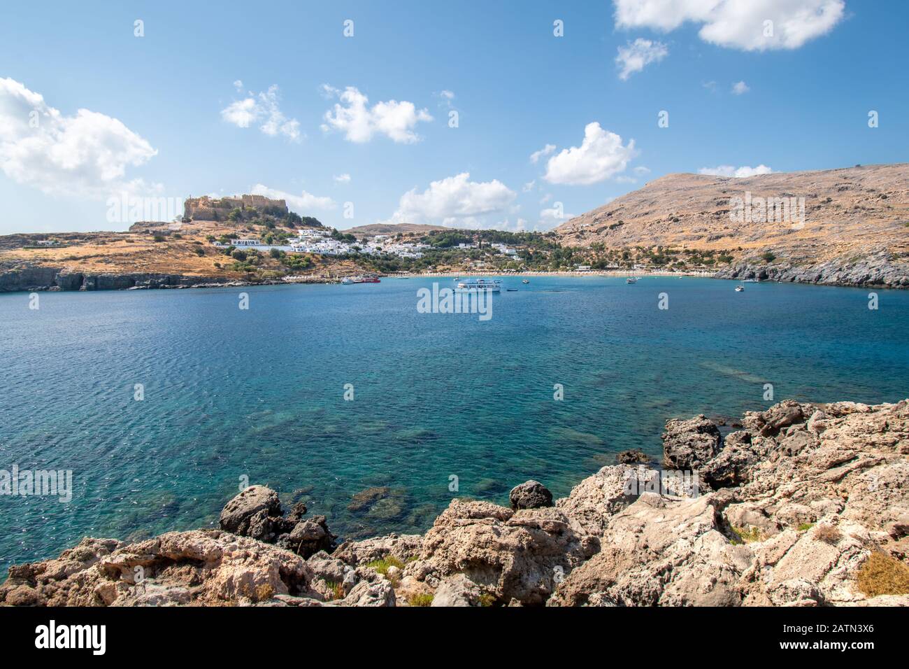 Baie de Lindos avec bateaux, maisons blanches du village de Lindos et Acropole en arrière-plan (Rhodes, Grèce) Banque D'Images