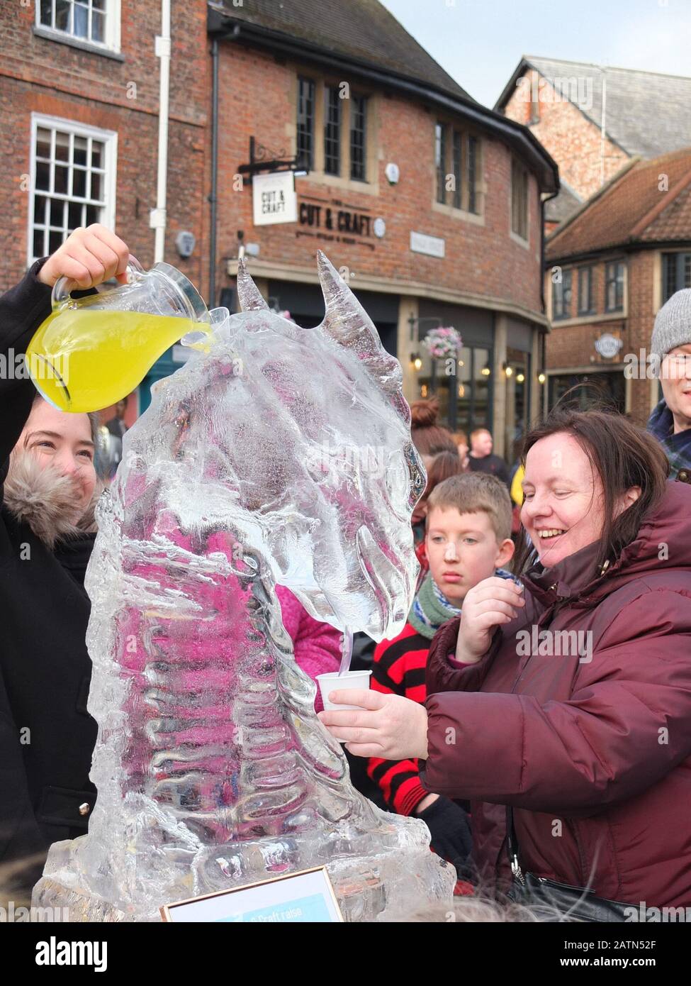 Une dame attend avec une tasse à une sculpture interactive « Dragon Luge » en forme de dragon à York ICE Trail 2020 que vous pouvez verser jus Banque D'Images