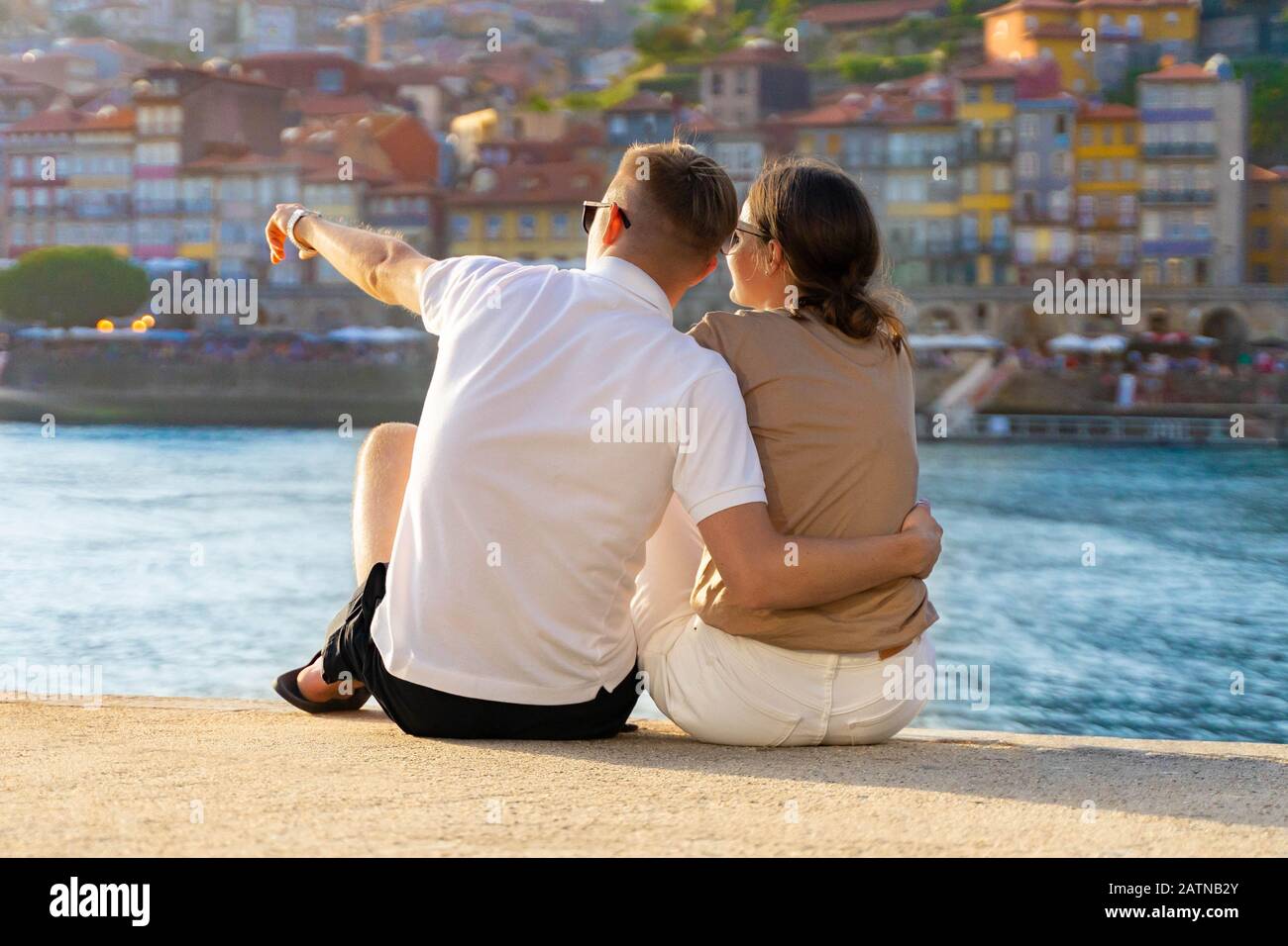 Couple amoureux, hugging, boire du vin et profiter de la vue sur le coucher du soleil à Porto, Portugal. Amoureux de la vue arrière. Panorama de la vieille ville de Porto à la rivière Duoro. Homme poin Banque D'Images