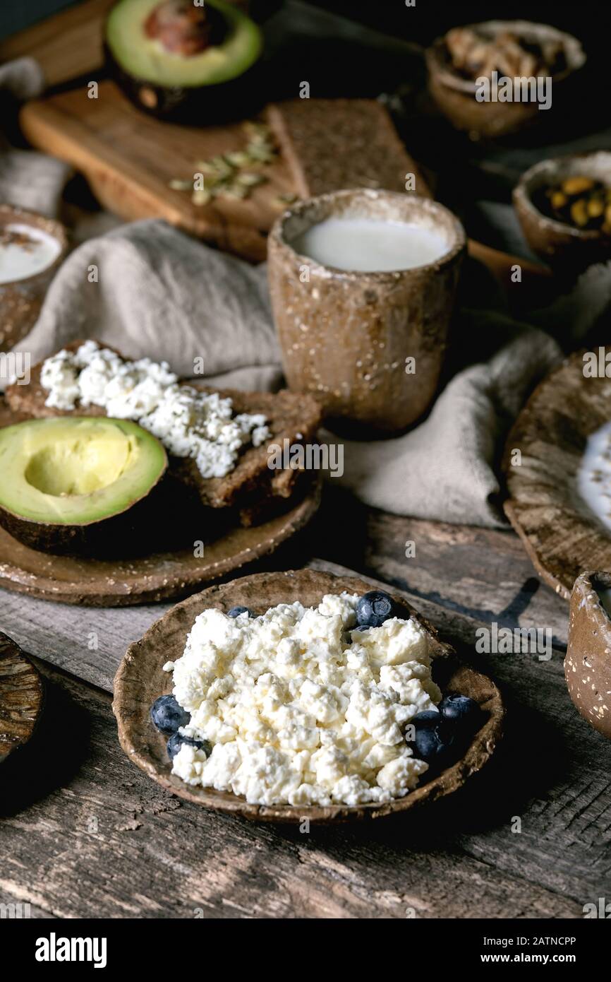 Petit déjeuner sain. Assortiment de plats de petit déjeuner composé de blé, yaourt, kéfir, fromage cottage, avocat, pain de seigle, graines, noix et baies i Banque D'Images