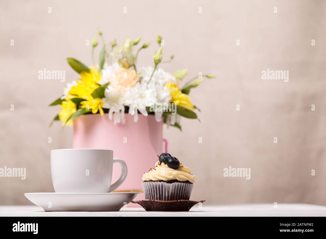 Tasse de cacao avec guimauves, un cupcake avec crème fouettée et bleuets, un bouquet de fleurs printanières et une couverture douce en arrière-plan. Valents Banque D'Images