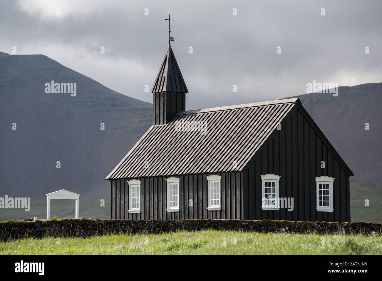 Vue détaillée de l'église en bois noir en face d'une chaîne de montagne à Budir, Islande Banque D'Images