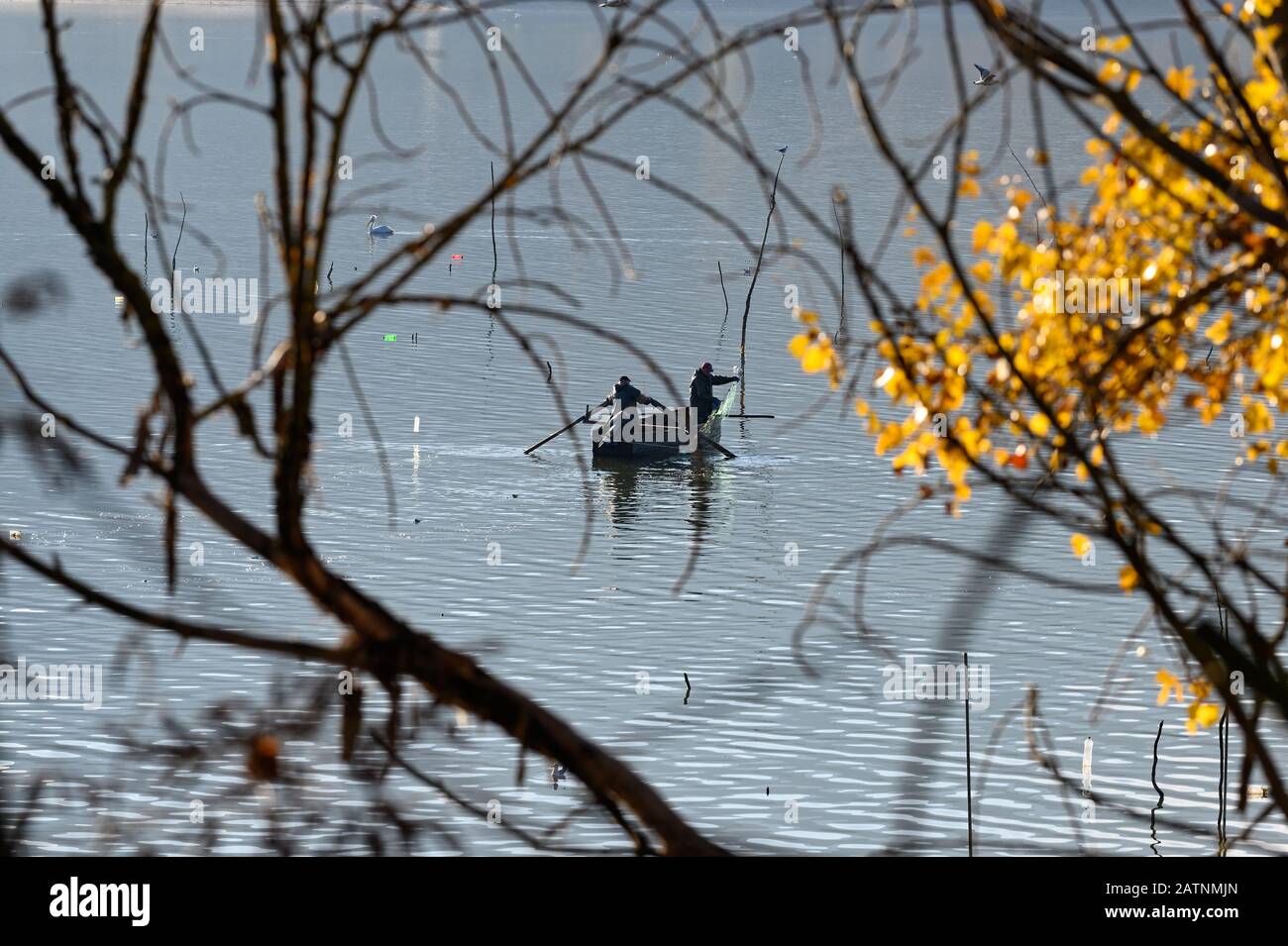 Vue à distance de deux pêcheurs travaillant dans un bateau traditionnel en bois du lac Kerkini dans le nord de la Grèce Banque D'Images