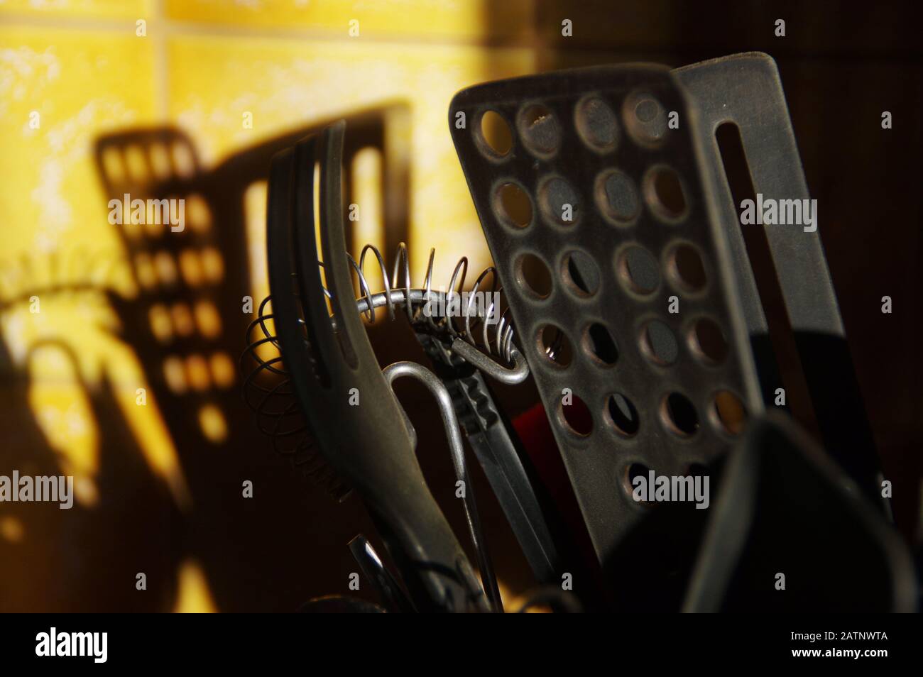 Outils de cuisine qui jettent une ombre sur le mur de céramique. Matin dans la cuisine. Banque D'Images