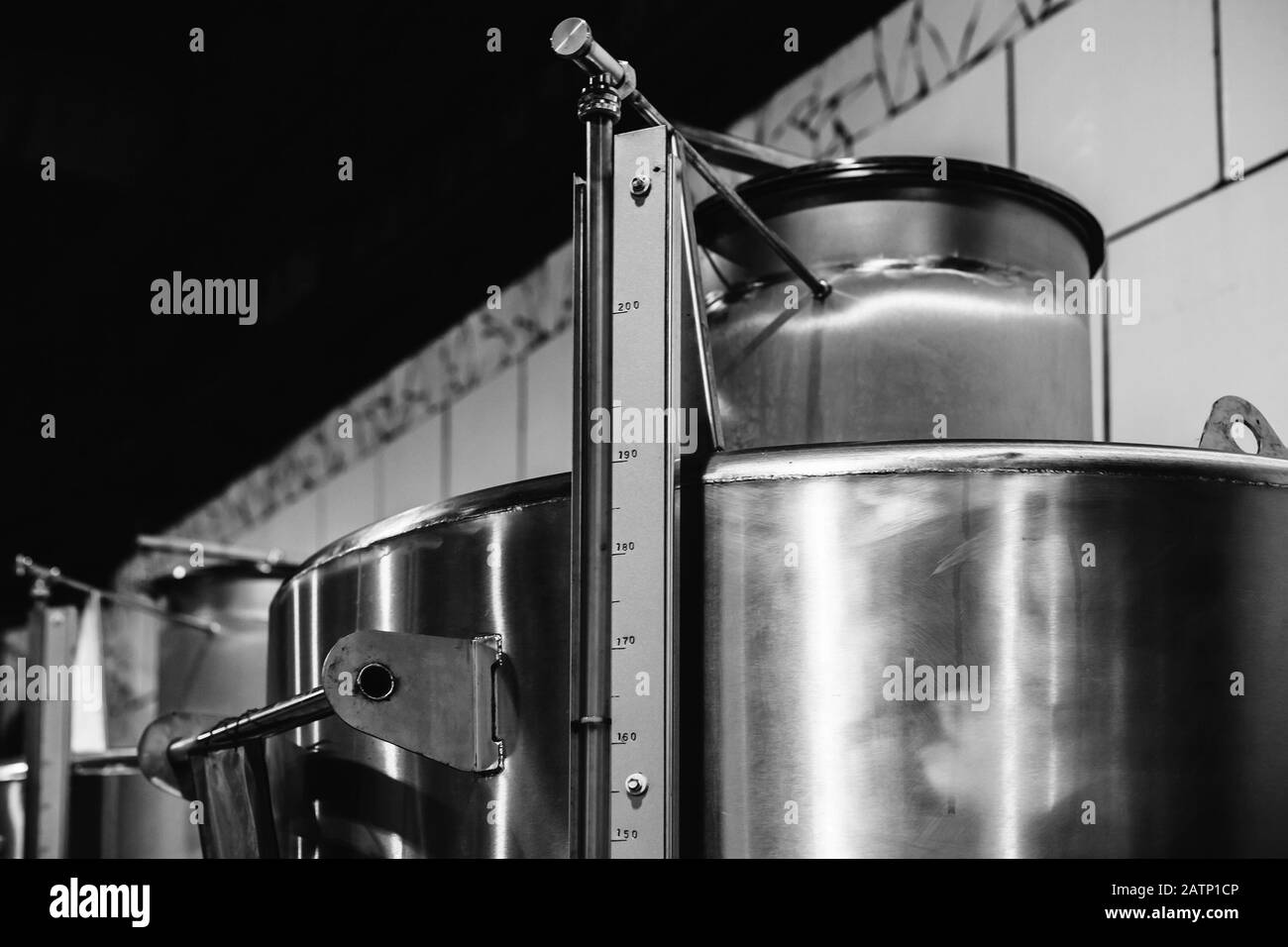 Fûts en acier inoxydable dans une rangée, équipement d'usine de vin. Photo en noir et blanc Banque D'Images