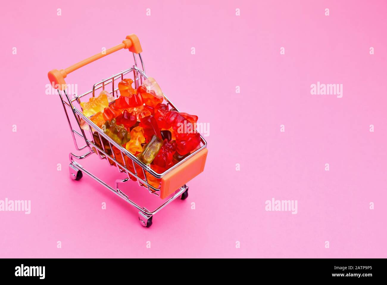 Panier plein de bonbons d'ours de gummy colorés sur fond rose Banque D'Images