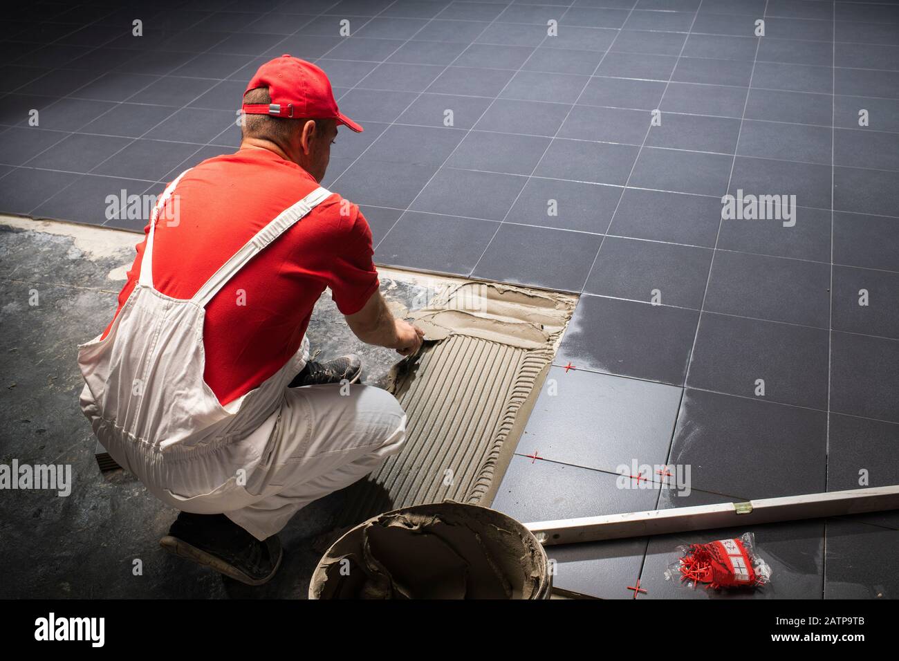 Un travailleur de la construction La mise de nouvelles tuiles de plancher. Banque D'Images