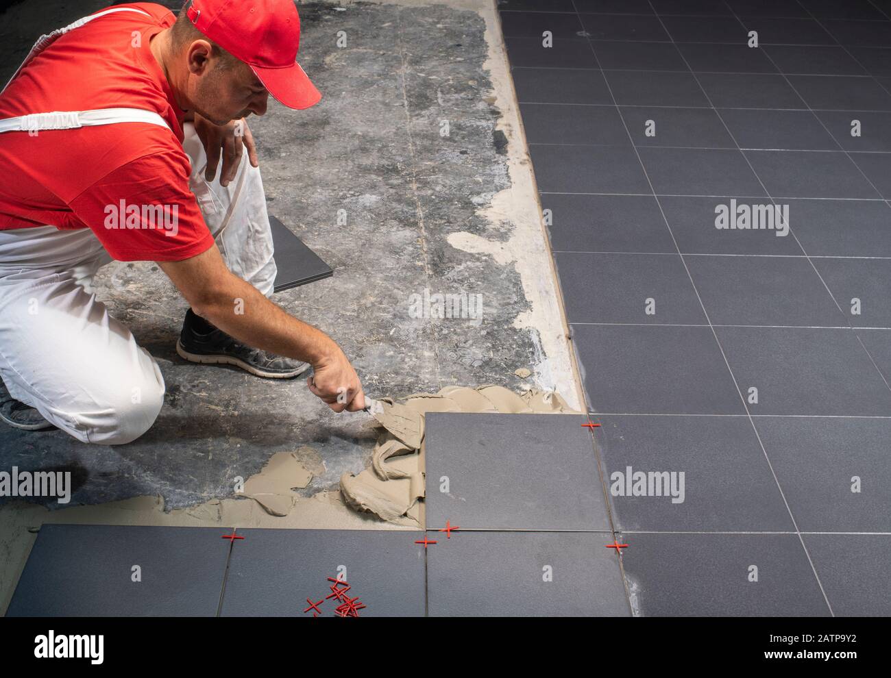 Un travailleur de la construction La mise de nouvelles tuiles de plancher. Banque D'Images