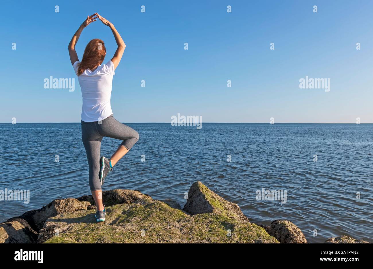 Pose de yoga pour femme donnant sur l'océan Banque D'Images