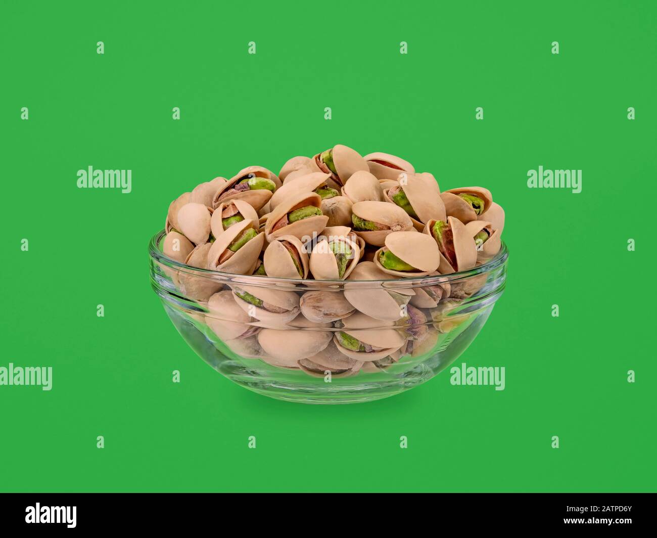 bol en verre de pistaches sur fond vert Banque D'Images