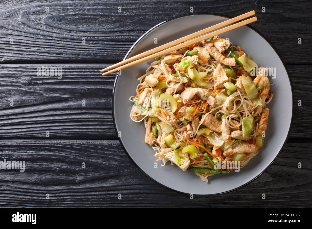 Servir le bihon de nouilles de riz philippin avec des légumes et de la viande dans une assiette sur la table. Vue de dessus horizontale Banque D'Images