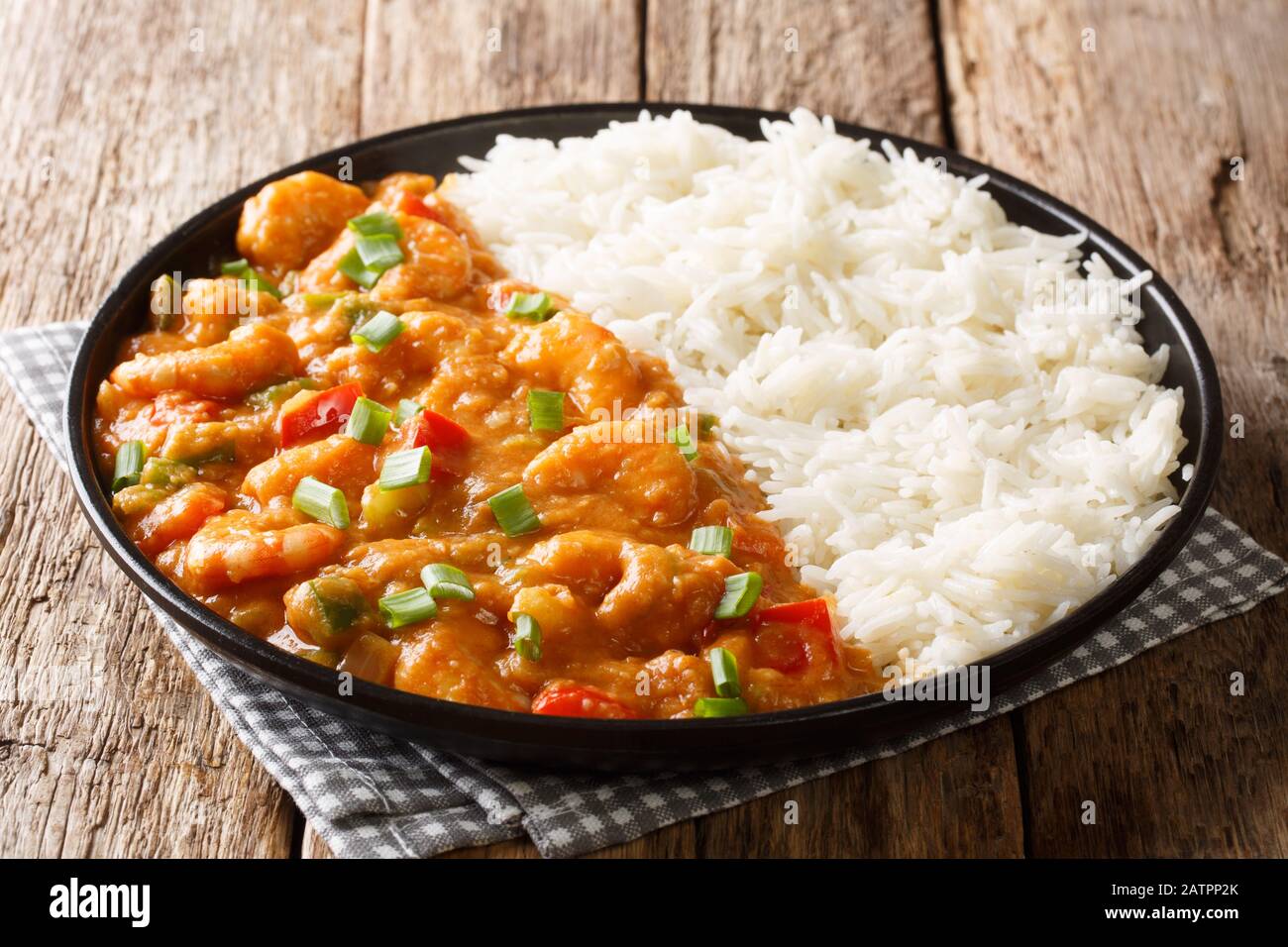 Portion de crevettes touffee avec légumes et sauce servis avec fermeture de riz dans une assiette sur la table. Horizontale Banque D'Images