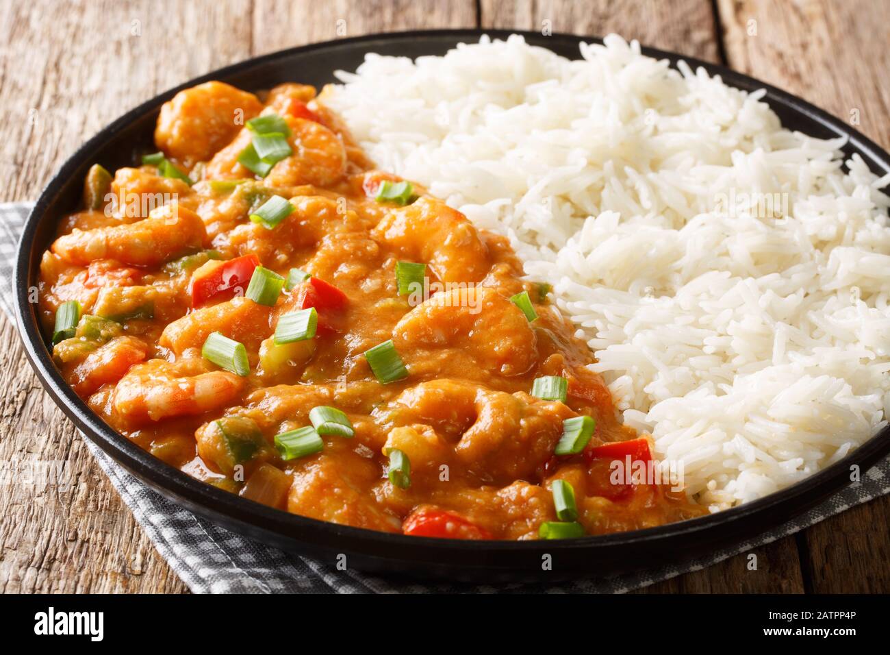 Plat d'Etouffee de crevettes créoles avec céleri, oignon et poivre cuit dans la sauce roux servi avec le riz dans une assiette sur la table. Horizontal Banque D'Images