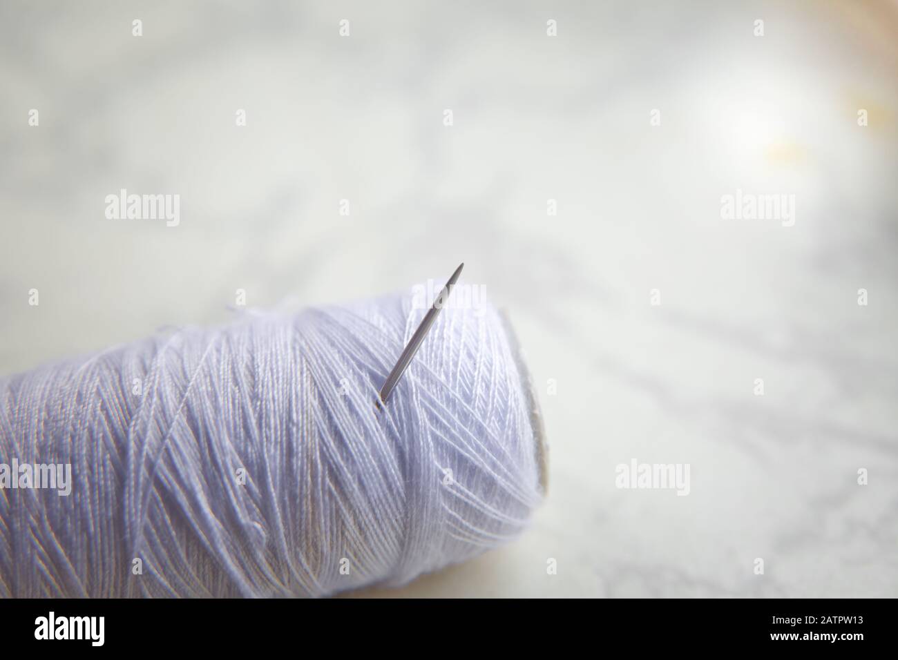 Bobine blanche avec aiguille isolée sur blanc .gros-plan de fil à coudre avec aiguille à broder. Métiers d'art et concepts de bricolage . Aiguille sur filetage blanc blanc Banque D'Images