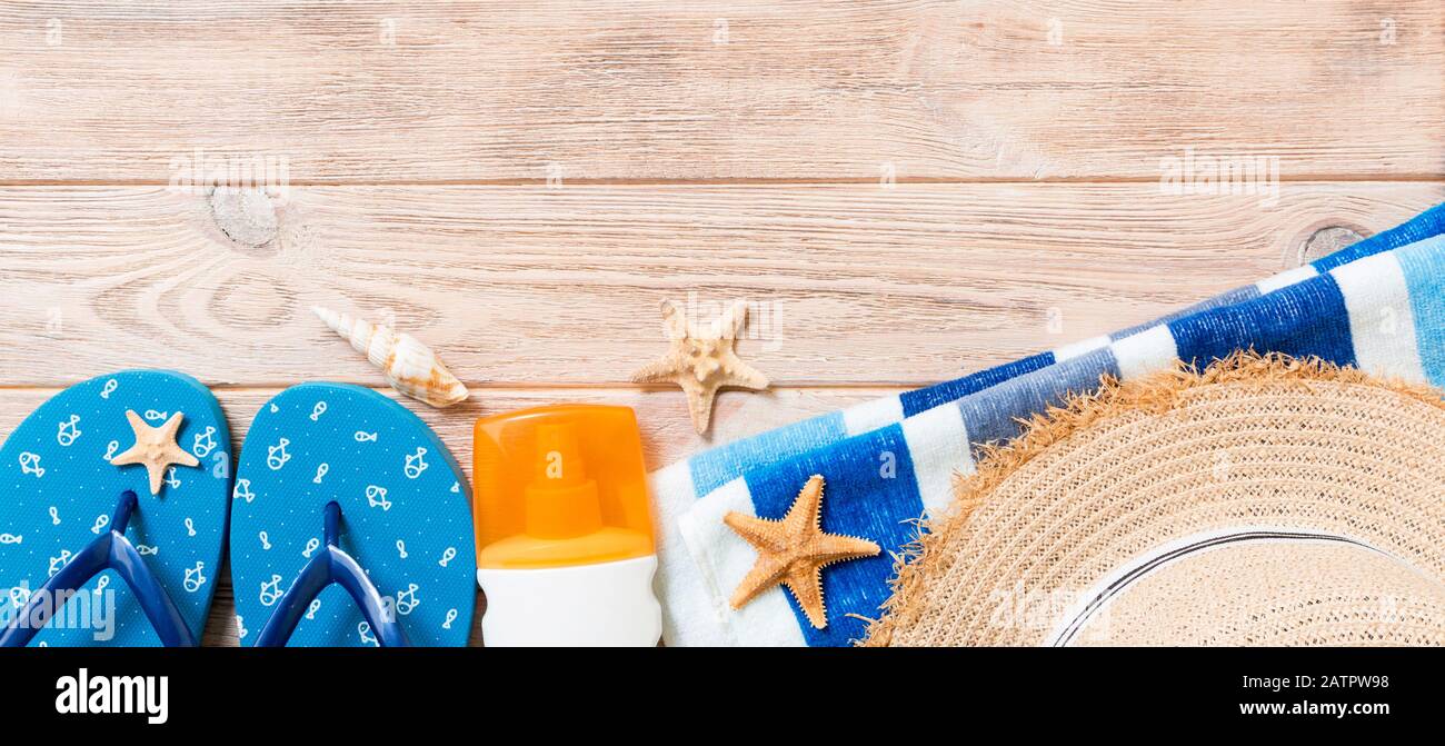 tongs, chapeau de paille, étoiles de mer, bouteille de crème solaire, spray de lotion pour le corps sur fond en bois bannière vue dessus . plat laïque été plage accessoires dos Banque D'Images