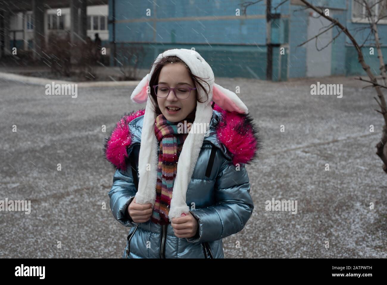 jolie petite fille avec capuche et oreilles. fille dans une rue de lapin de  chapeau. Belle jeune femme mignonne en végan bleu et manteau en fausse  fourrure pose sur la ville urbaine