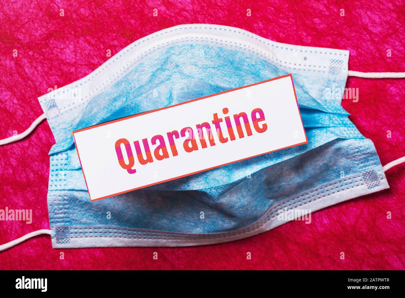 Masque médical de couleur bleue et feuille de papier avec inscription sur fond rouge, vue de dessus. Concept de quarantaine Banque D'Images