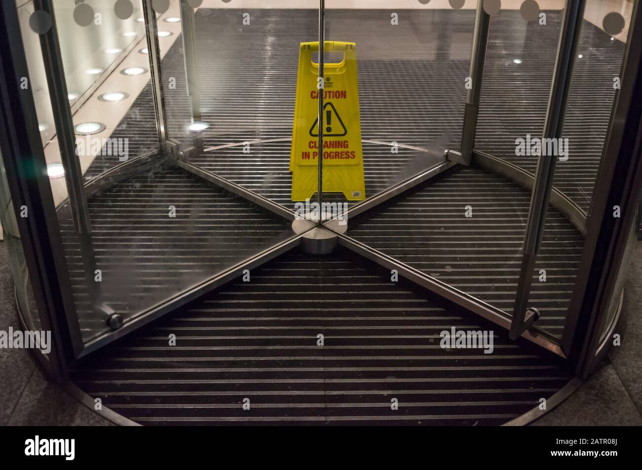 Attention jaune, panneau de nettoyage en cours au milieu de certaines portes tournantes d'un immeuble de bureaux. Londres Banque D'Images