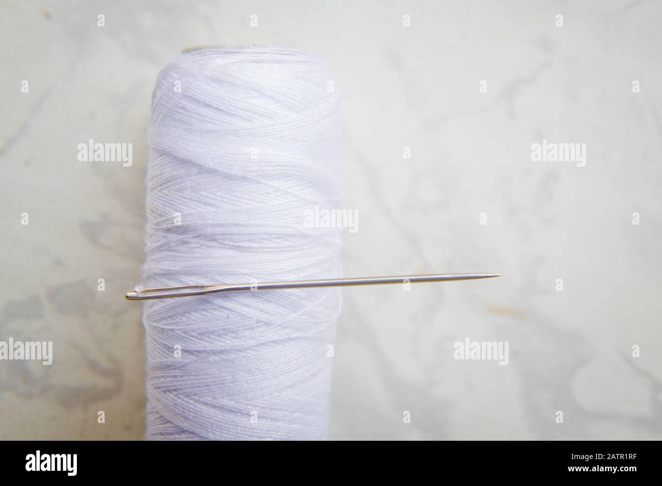 Bobine blanche avec aiguille isolée sur blanc .gros-plan de fil à coudre avec aiguille à broder. Métiers d'art et concepts de bricolage . Aiguille sur filetage blanc blanc Banque D'Images