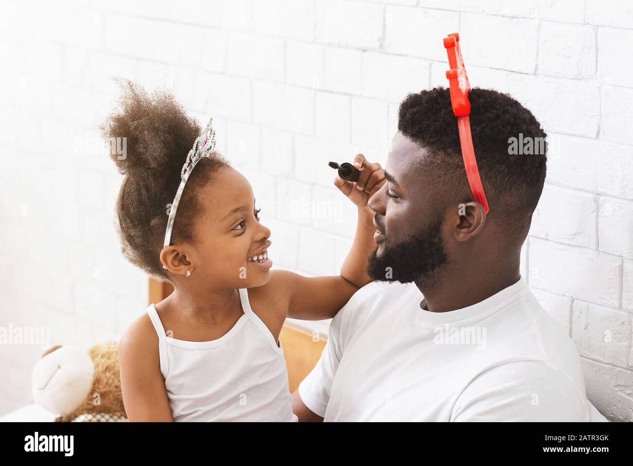 Petite fille noire qui met sur le visage de son père Banque D'Images