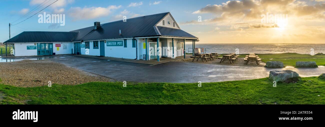 Panorama du restaurant Lobster Pot juste à côté du phare de Portland Bill juste après le lever et le soleil donnant une lueur chaude sur la mer. Banque D'Images