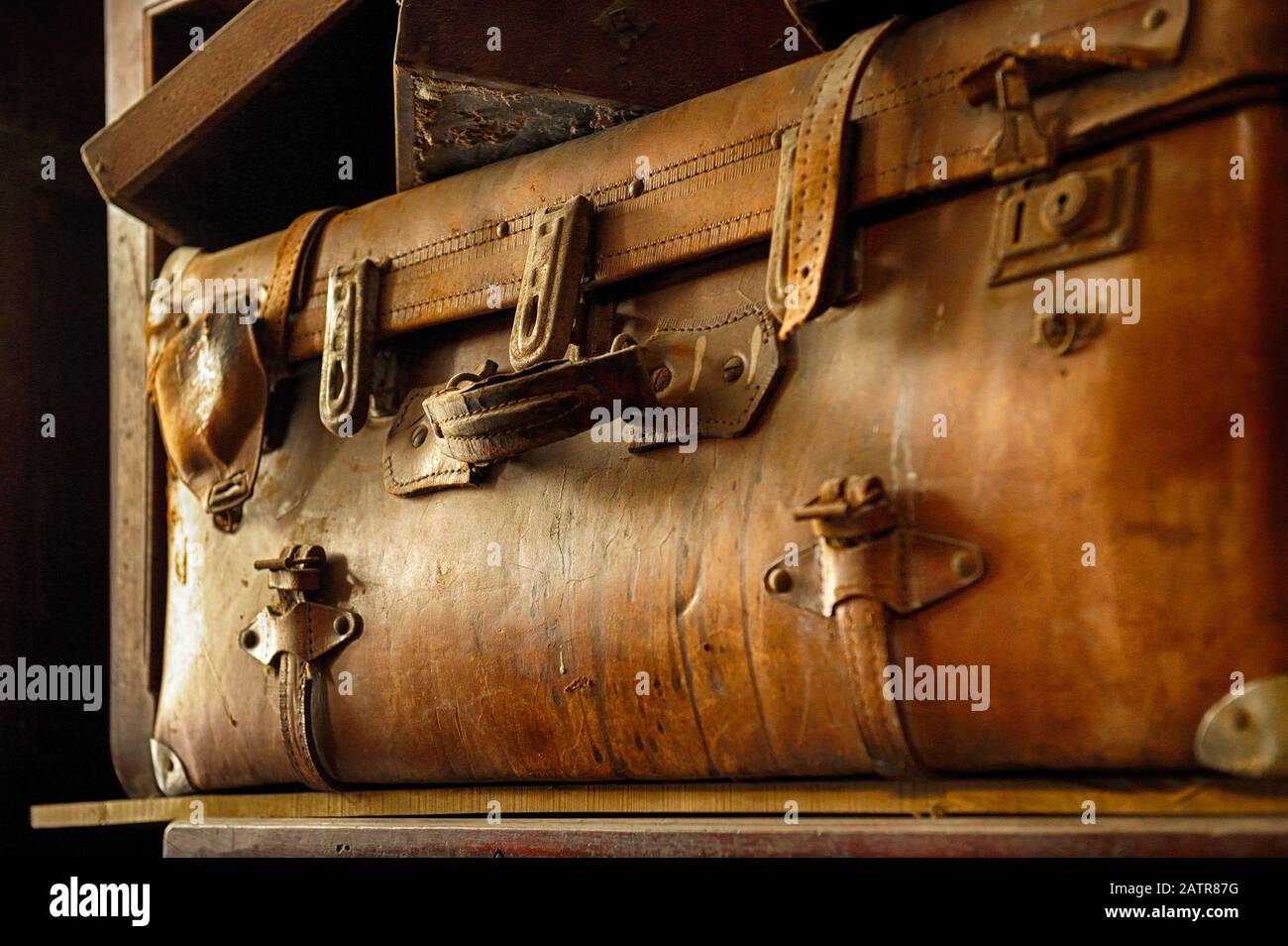 Valise en cuir brun vintage dans un dressing poussiéreux. Banque D'Images