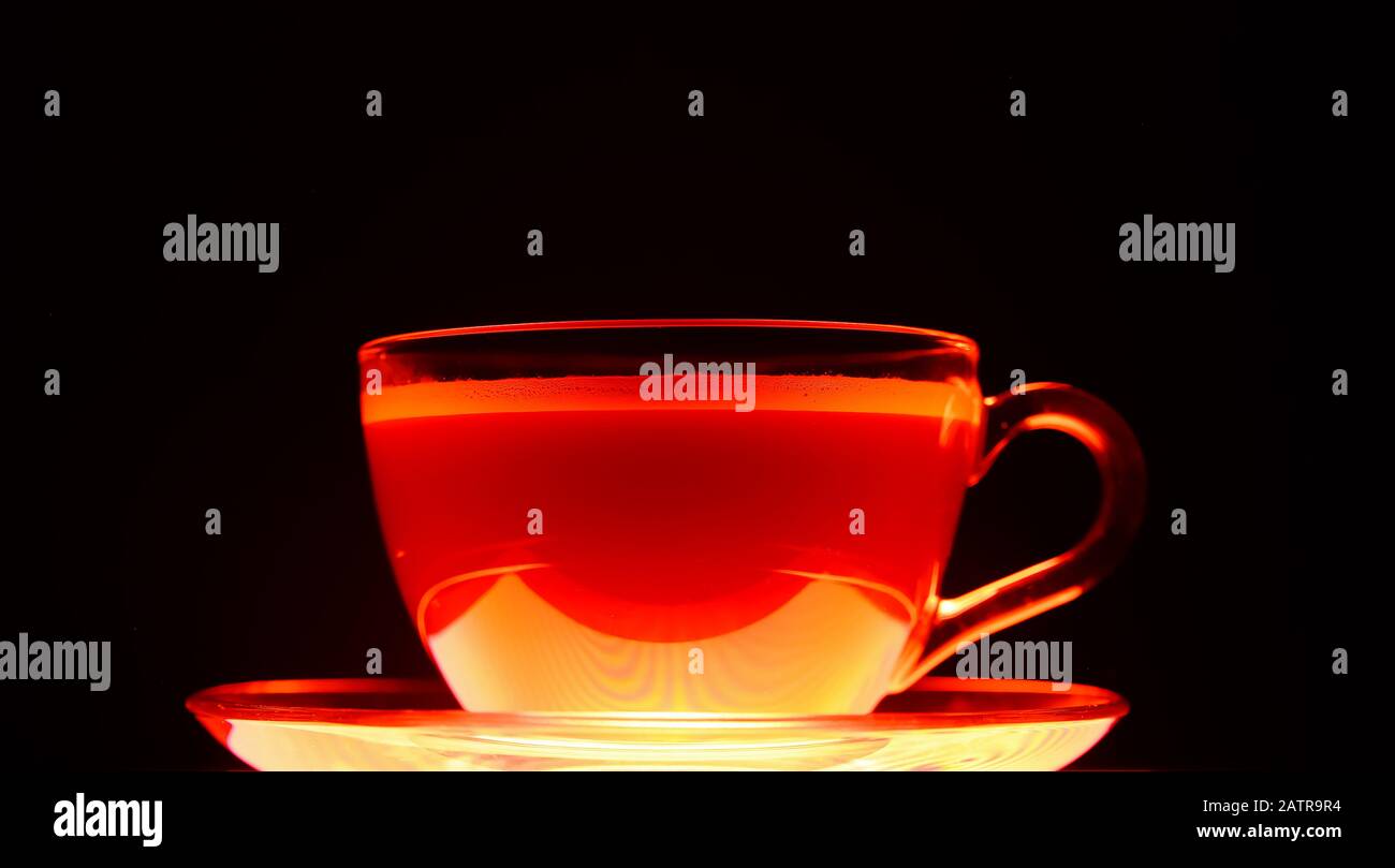 Gros plan d'une tasse de café marron transparente isolée illuminée en rouge clair et noir Banque D'Images