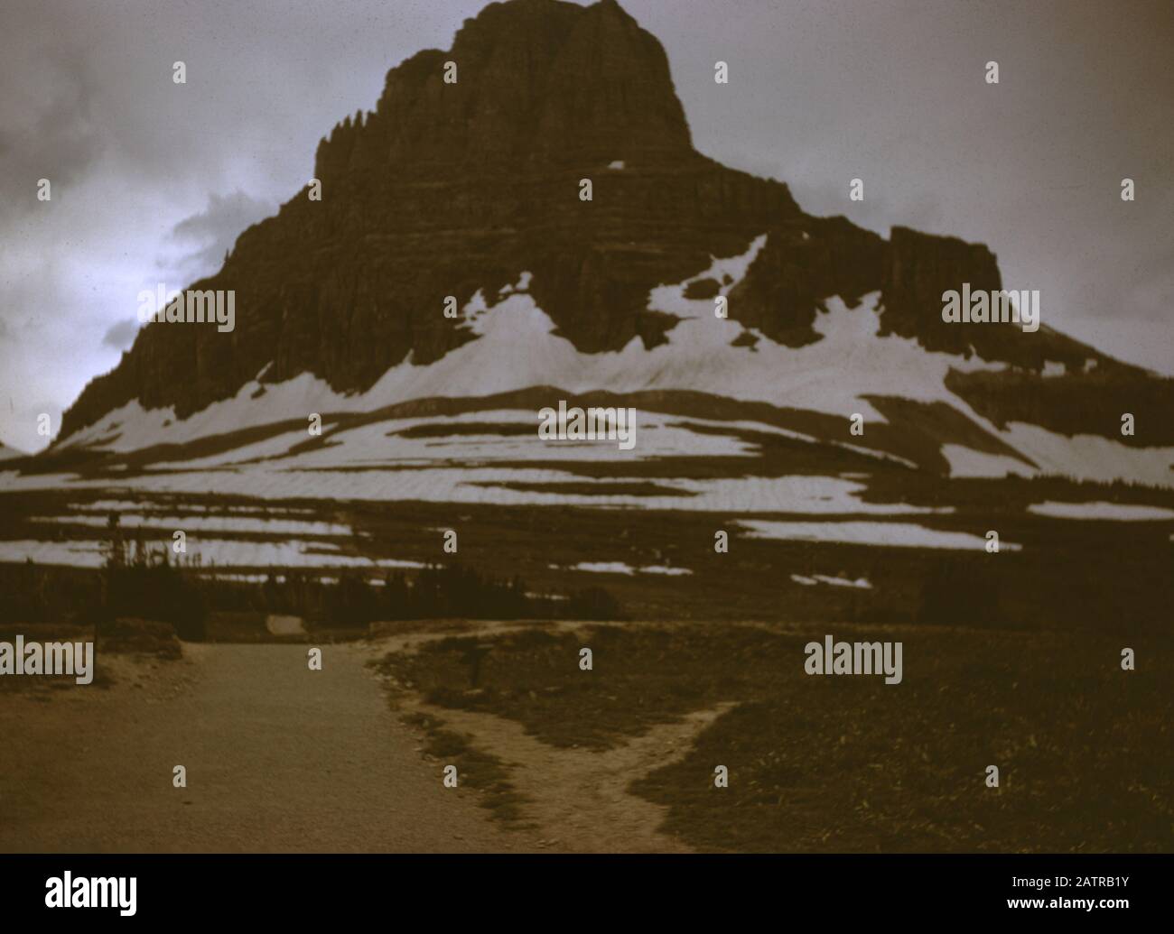 Photographie vernaculaire prise sur une transparence de film analogique de 35 mm, considérée comme représentant la montagne enneigée pendant la journée, 1965. Les sites/sites détectés incluent le parc national des Glaciers. Les principaux sujets/objets détectés sont Les paysages Montagneux, la montagne, le ciel, le paysage et le rocher. () Banque D'Images