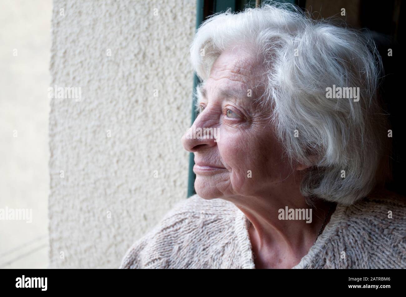 Portrait de la vieille femme regardant sur une fenêtre. Banque D'Images
