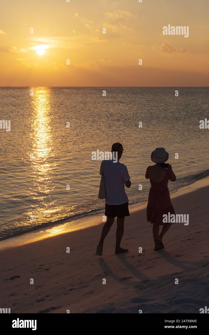 Couple sur la plage - un couple marchant sur une plage tropicale en regardant le coucher du soleil sur l'océan Indien, les Maldives, Asie Banque D'Images