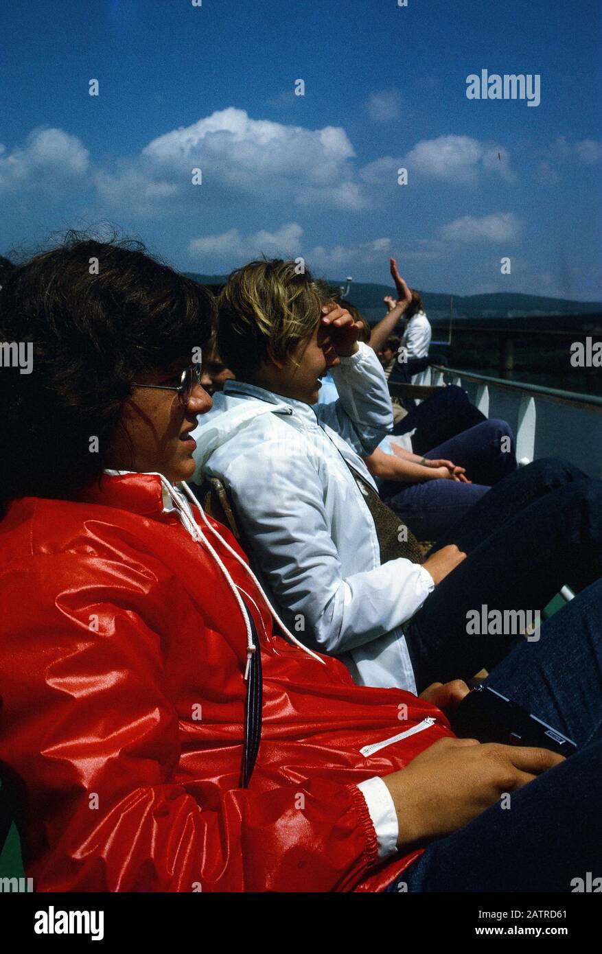 Photographie vernaculaire prise sur un film analogique de 35 mm transparent, considérée comme représentant des personnes assis sur une chaise noire pendant la journée, la lecture sur un navire, 1970. Les principaux sujets/objets détectés incluent le véhicule et le déplacement. () Banque D'Images