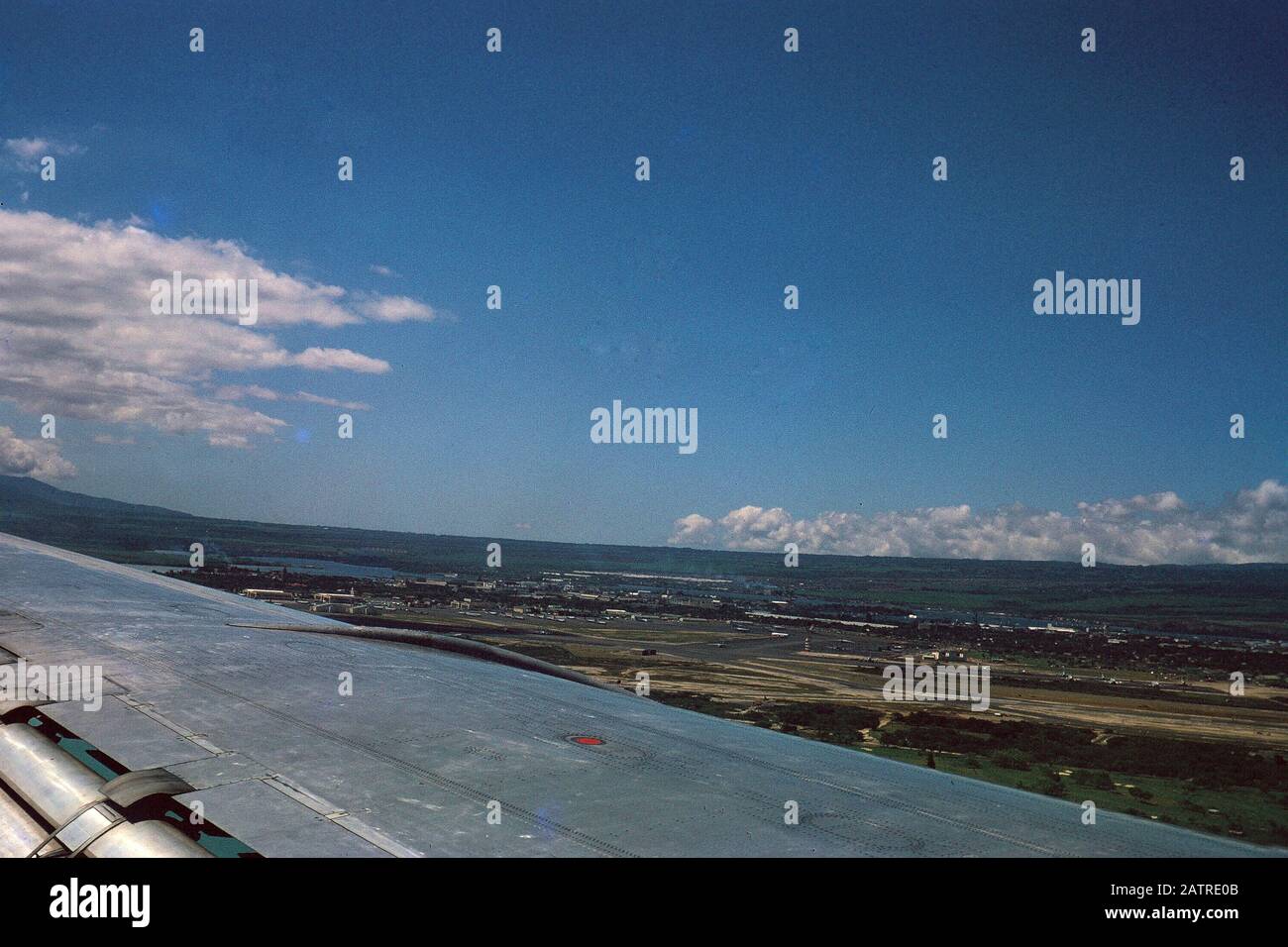 Photographie vernaculaire prise sur une transparence de film analogique de 35 mm, vue de paysage de la fenêtre d'avion avec aile visible, 1970. Les principaux sujets/objets détectés sont le ciel, la mer et le véhicule. () Banque D'Images