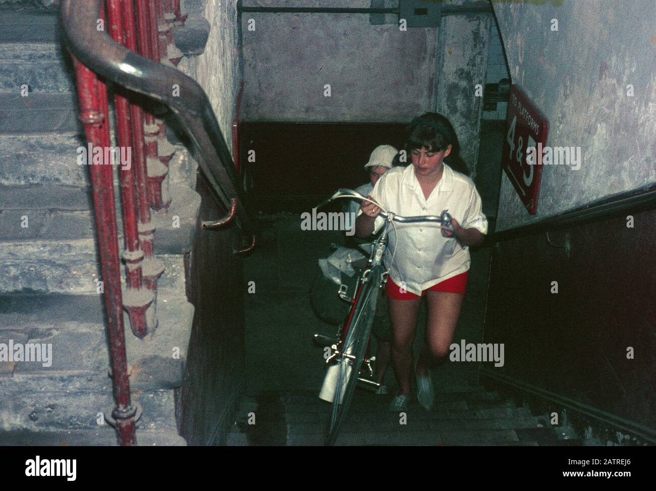 Photographie vernaculaire prise sur un film analogique de 35 mm transparent, considérée comme représentant des personnes transportant des vélos en haut d'un escalier, 1970. () Banque D'Images