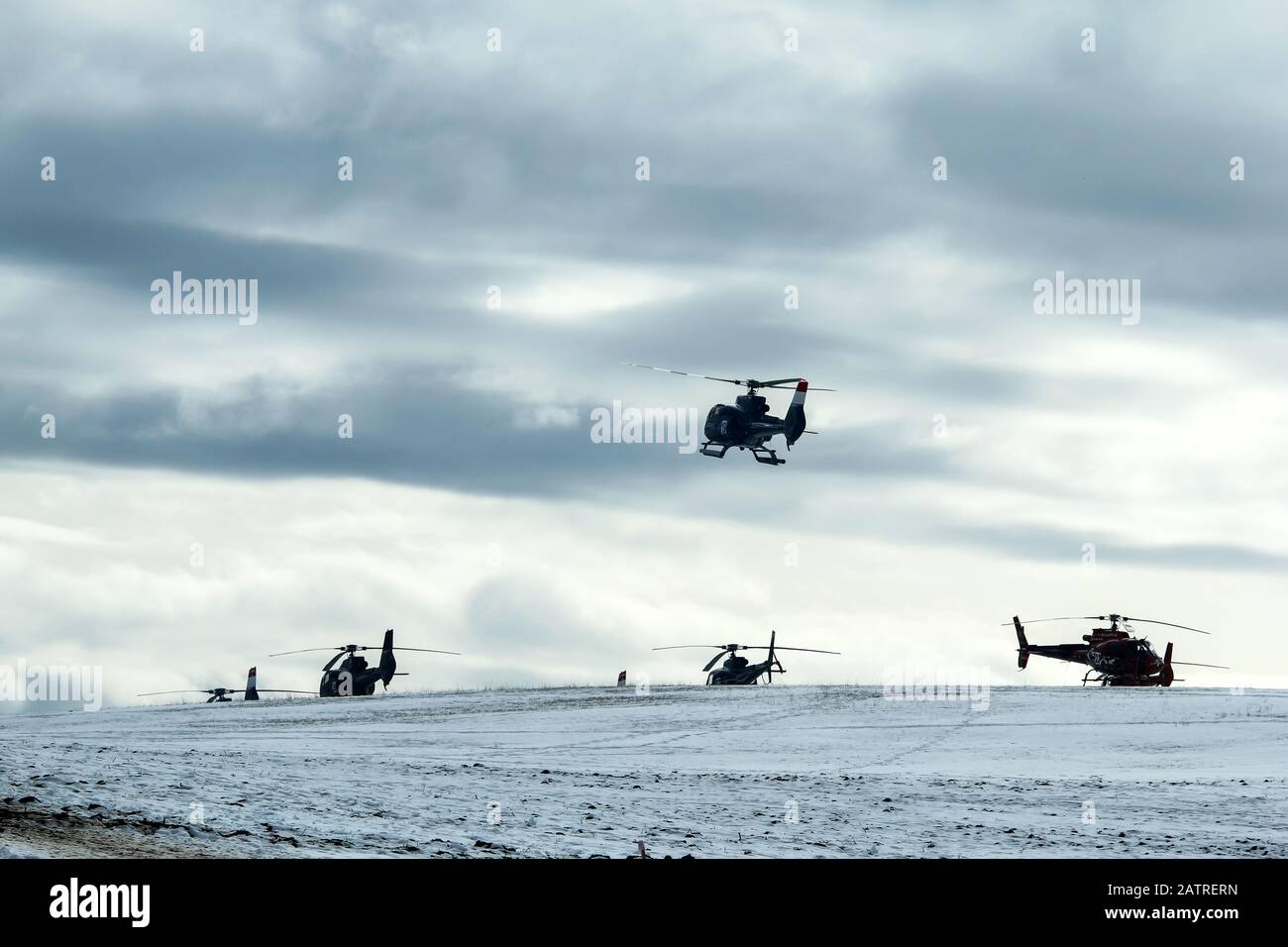 Une image atmosphérique montre l'atterrissage de l'hélicoptère sur le champ enneigé. D'autres hélicoptères sont debout sur le sol. Banque D'Images