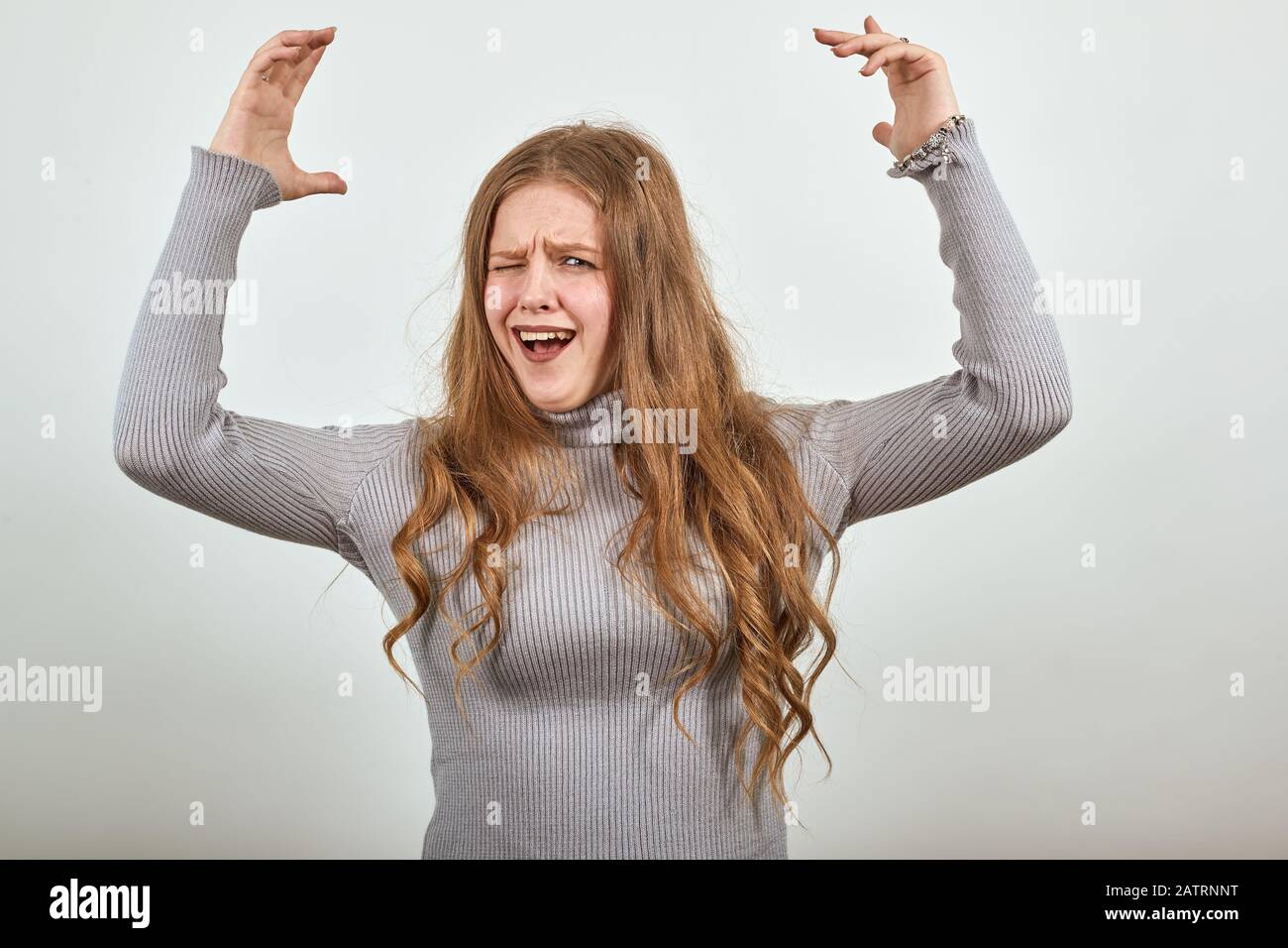 une femme en pull gris soulève joyeusement ses mains cries avec plaisir Banque D'Images