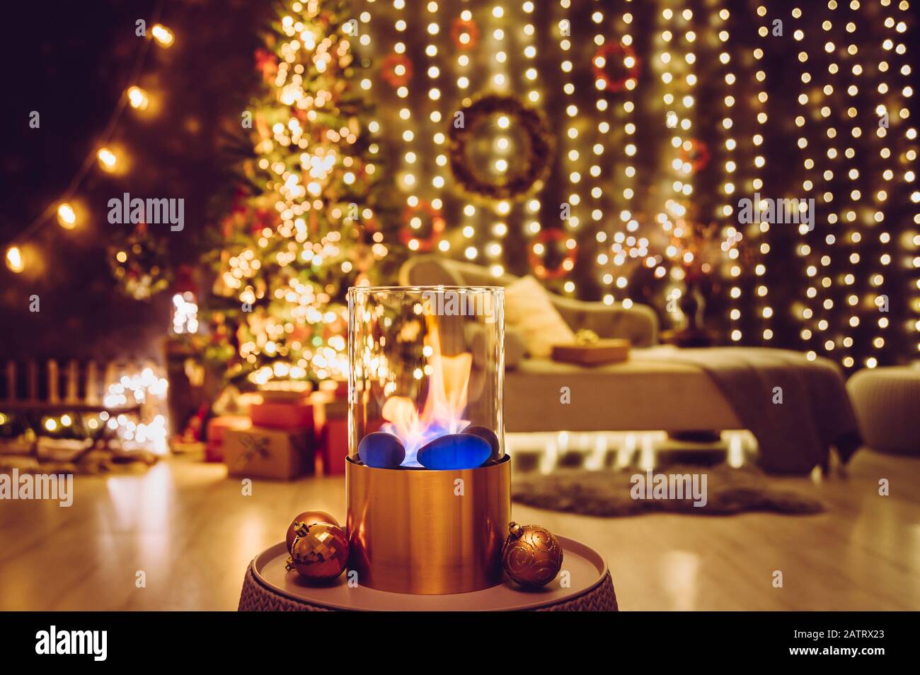 Foyer en verre et en cuivre métallique portable sur pied et moderne brûlant du gaz bio-éthanol sur la table du salon avec un agréable réveillon de Noël Banque D'Images