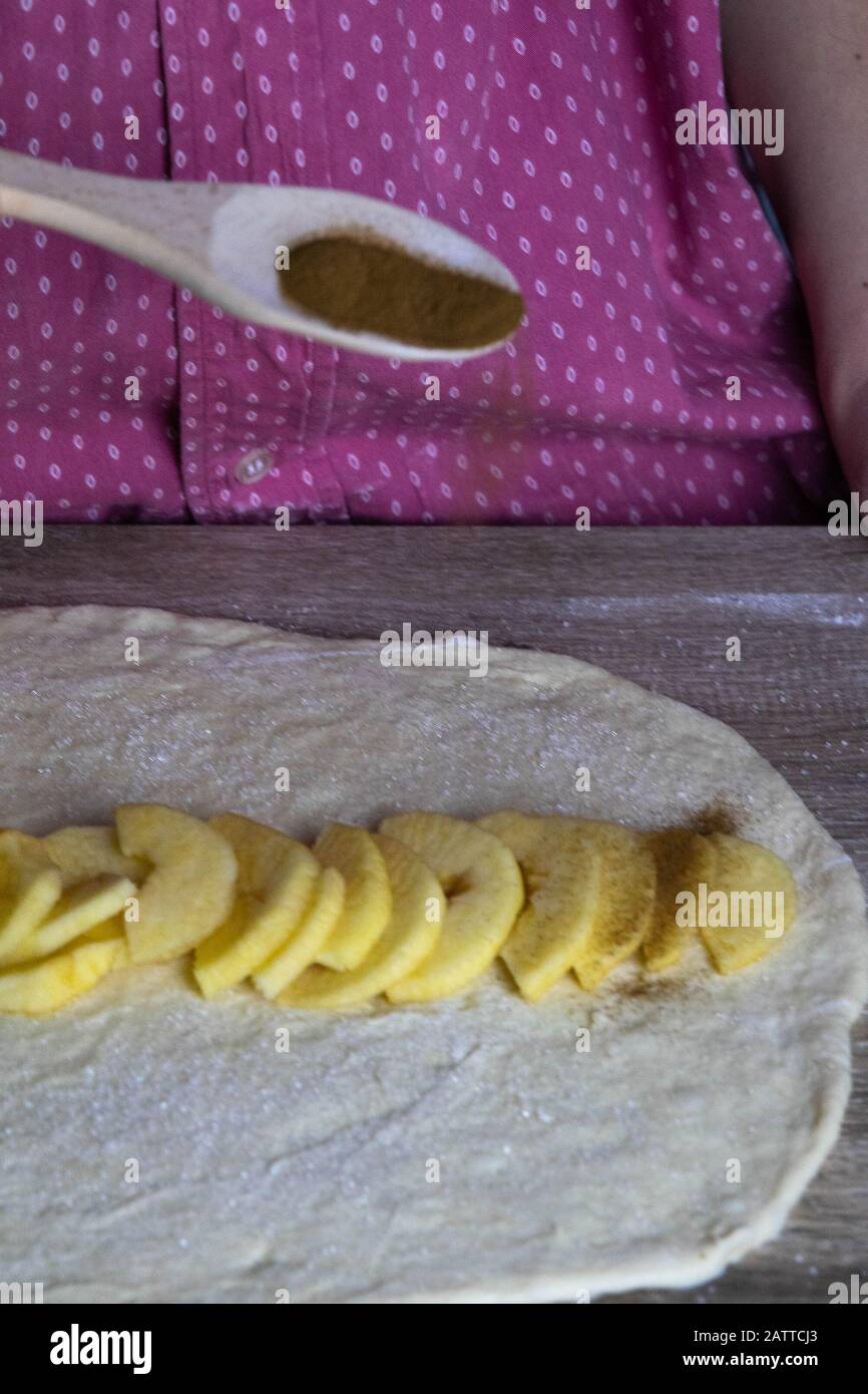 Main pour femme saupoudrée de cannelle. Tranches de pommes et de cannelle, étalées sur le test. Banque D'Images