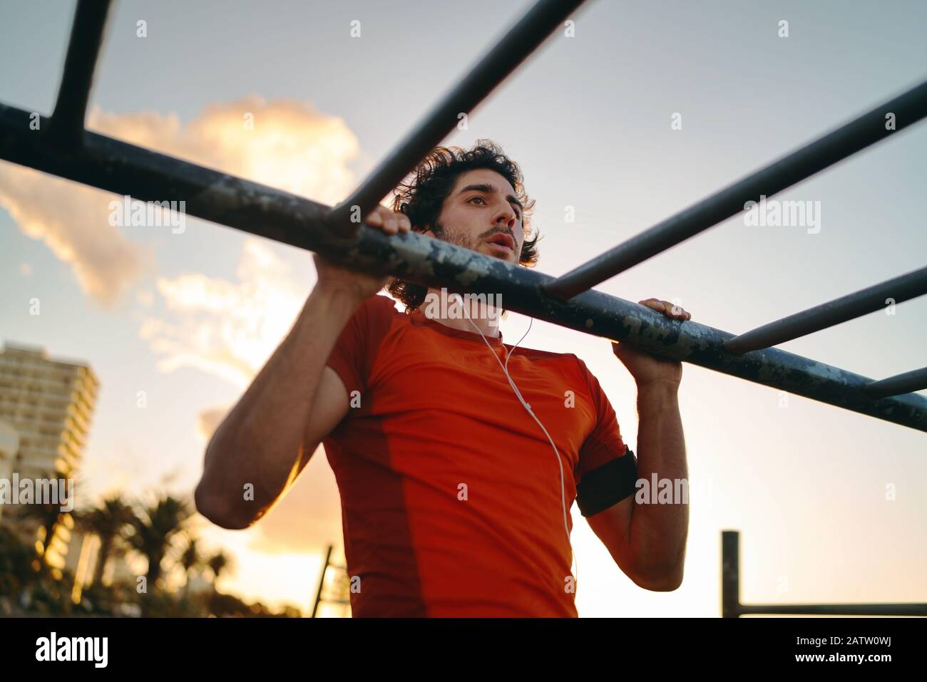 Gros plan d'un jeune athlète masculin faisant des exercices au bar dans le parc de la salle de sport contre le ciel - homme faisant des pull-ups à l'extérieur Banque D'Images