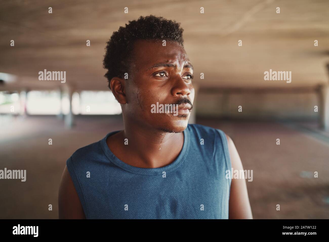 Portrait d'un jeune homme sportif afro-américain fatigué qui transpirant après une séance d'entraînement à l'extérieur regardant loin Banque D'Images