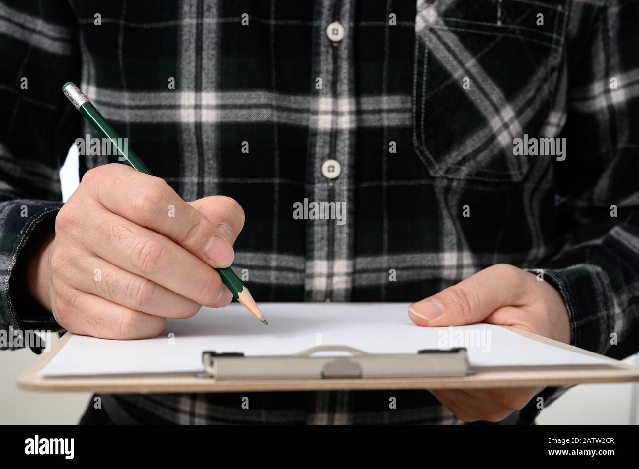 Gros plan de la main d'un homme signant un document avec un presse-papiers Banque D'Images