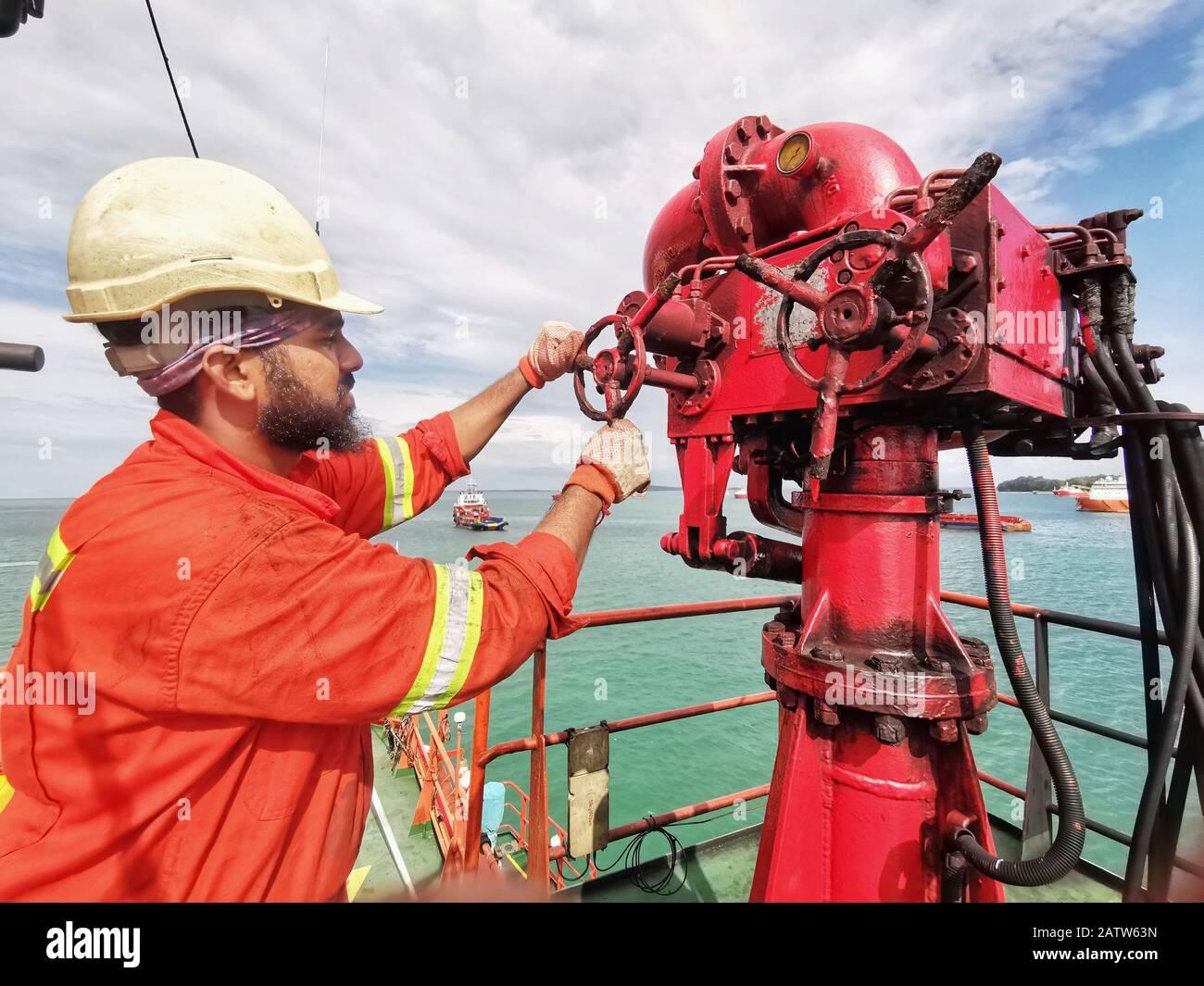 Les membres de l'équipage maritime offshore effectuent des opérations d'entretien et de graissage à l'aide du moniteur de lutte contre les incendies IFOP à bord du navire Banque D'Images