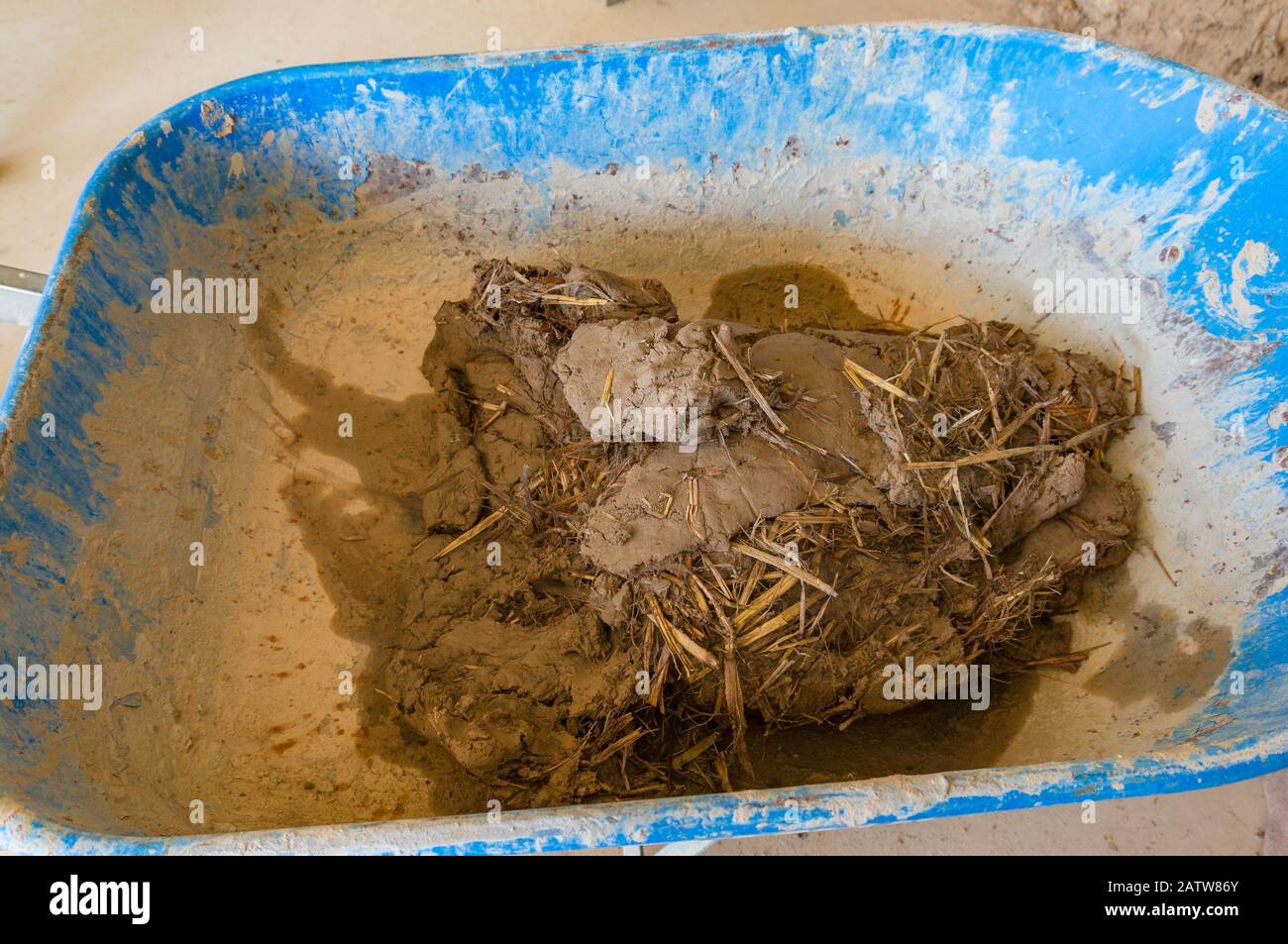 Argile, saleté avec paille dans la roue barrow. Techniques de construction de bâtiments écologiques de cloom Banque D'Images