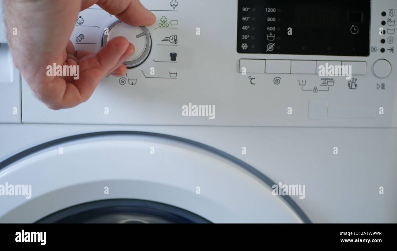 Homme Utilisant Un Lave-Linge Moderne Appareil Pour Laver Et Nettoyer Les Vêtements Sales Banque D'Images