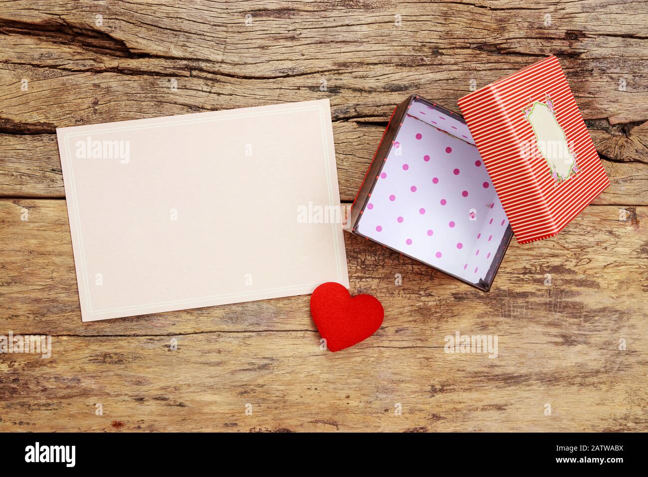 carte de vœux rose vierge avec cadre de bordure et coffret cadeau rouge vide avec couvercle ouvert, décorer avec coeur rouge sur fond en bois Banque D'Images