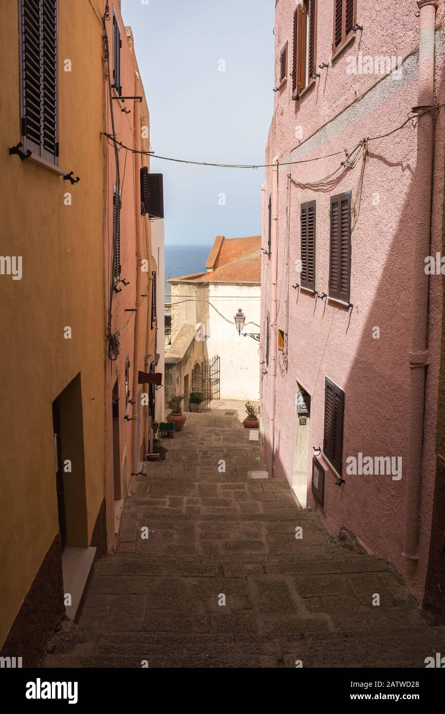 Rue étroite de la ville, en partie dans une ombre. Façades colorées des maisons avec fenêtres avec volet. Horizon de la mer en arrière-plan. Roulettes Banque D'Images